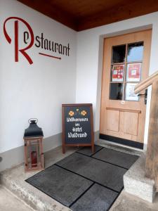 una señal frente a un edificio con una puerta en Hotel Restaurant Waldrand , Isenfluh 