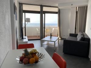 ein Wohnzimmer mit einem Tisch und einer Obstschale darauf in der Unterkunft Vista Dorada al mar balcón-Wifi By CanariasGetaway in Las Palmas de Gran Canaria