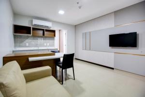 a living room with a couch and a table and a tv at Advanced Hotel & Flats Cuiabá in Cuiabá