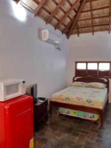 a bedroom with a bed and a small refrigerator at Muyuyo Lodge in Ayangue