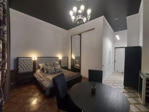 a bedroom with a bed and a table and a chandelier at In the heart of the city in Kharkiv