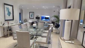 une salle à manger avec une table en verre et des chaises blanches dans l'établissement Casa Das Palmeiras, à Loulé