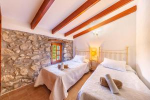 twee bedden in een kamer met een stenen muur bij Villa Mala Garbo in Pollença