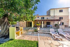 een huis met twee witte stoelen in een tuin bij Villa Mala Garbo in Pollença