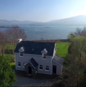 ein großes weißes Haus mit Blick auf das Wasser in der Unterkunft Heron Water Cottage in Killarney