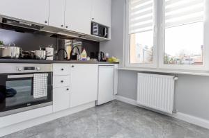 - une cuisine avec des placards blancs et une cuisinière dans l'établissement CR Apartament Centrum Zamenhofa 1, à Białystok