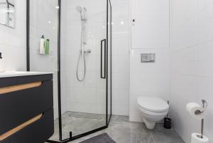 La salle de bains blanche est pourvue d'une douche et de toilettes. dans l'établissement CR Apartament Centrum Zamenhofa 1, à Białystok