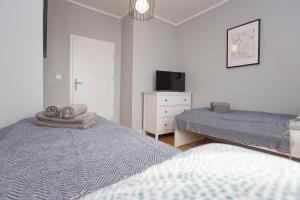 sypialnia z 2 łóżkami, telewizorem i komodą w obiekcie CR Apartament Centrum Zamenhofa 1 w mieście Białystok