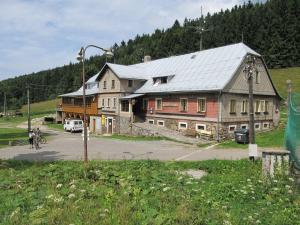 a large wooden building on a street next to a road at Horská bouda Čihalka in Olešnice v Orlických horách