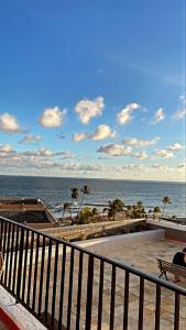 a person sitting on a bench looking at the ocean at EDIFÍCIO METROPOLE ONDINA in Salvador
