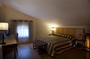 a bedroom with a bed and a desk and a window at Virgilio Grand Hotel in Sperlonga