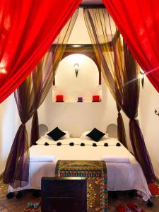Schlafzimmer mit einem Bett mit roten Vorhängen in der Unterkunft Riad Khabia & Spa in Marrakesch