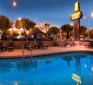 a swimming pool at night with a hotel sign at Temple Hotel in Didim