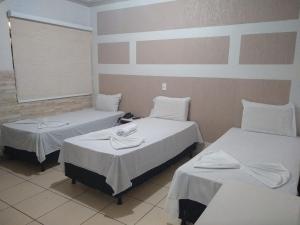 Rolim de Moura的住宿－Crystal Palace Hotel，一间设有两张带白色床单的床的房间