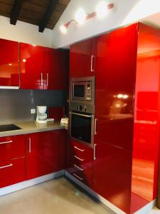 cocina roja con armarios rojos y microondas en Casa do Avô, en Sistelo