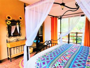 a bedroom with a canopy bed with a window at Hotel Boutique Jardín de Flores in Tlayacapan