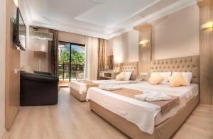 a hotel room with two beds and a television at Temple Beach Hotel in Didim