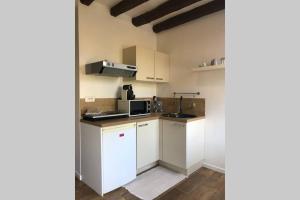 a kitchen with white cabinets and a microwave at Studio de la porte de Samois in Moret-sur-Loing