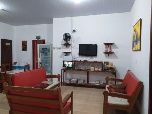 a living room with two chairs and a tv at Hostel Pousada do Tapajós in Alter do Chao