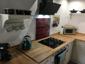 a kitchen with a stove top oven next to a microwave at La Tuilerie Grange (Adults only gite) with two en-suite double bedrooms in Le Bugue