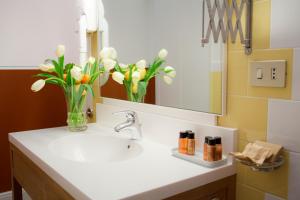 ein Badezimmer mit einem Waschbecken und einer Vase aus Blumen in der Unterkunft Piazza Di Spagna Prestige in Rom