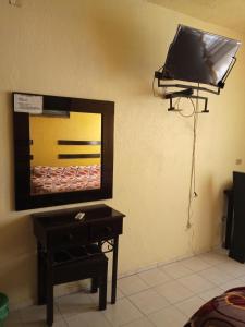 a mirror on a wall with a table and a tv at Hotel Posada del Ángel in Villahermosa
