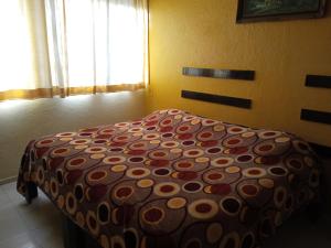 a bedroom with a bed with a polka dot blanket at Hotel Posada del Ángel in Villahermosa
