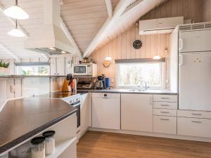 kuchnia z białymi urządzeniami i drewnianymi ścianami w obiekcie Holiday home Oksbøl L w mieście Oksbøl