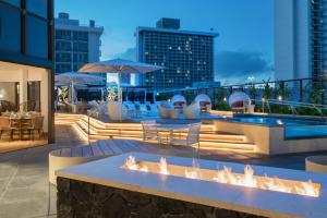 a rooftop patio with a fire pit and a pool at Hyatt Centric Waikiki Beach in Honolulu