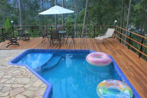 a swimming pool on a wooden deck with an umbrella at Bendito Recanto in Penedo