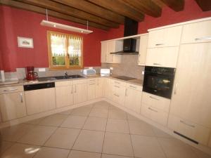 a kitchen with white cabinets and a red wall at Authentic chalet with terrace in Harreberg in Hommert