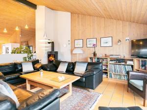 a living room with leather furniture and a fireplace at Five-Bedroom Holiday home in Hjørring 2 in Lønstrup