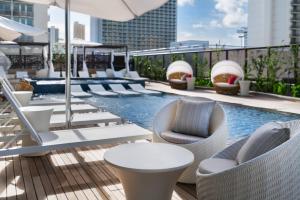 an outdoor pool with chairs and tables and a swimming pool at Hyatt Centric Waikiki Beach in Honolulu
