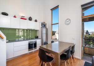 a kitchen with white cabinets and a wooden table and chairs at Triggerplant 4 in Dinner Plain