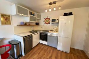 eine Küche mit einem weißen Kühlschrank und einem roten Stuhl in der Unterkunft Two Bedroom Garden Flat in Zone 2 London in London