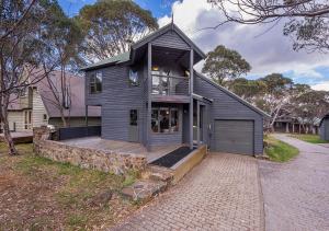 a black house with a wooden porch and a driveway at Montane in Dinner Plain