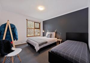 a bedroom with a bed and a chair and a window at Montane in Dinner Plain