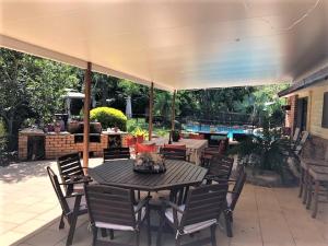 un patio con mesa, sillas y piscina en B&B Home in the Country, en Barellan Point