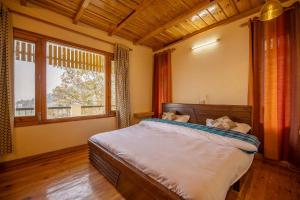 a bedroom with a large bed and a large window at StayVista at Brij Valley with Indoor Games & Bonfire in Rāmgarh