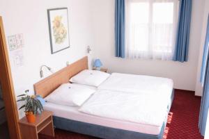 a bedroom with a white bed and a window at Hotel Schillerplatz in Öhringen