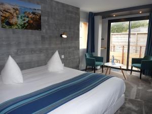 une chambre d'hôtel avec un lit, une table et des chaises dans l'établissement Hôtel des Rochers, à Perros-Guirec