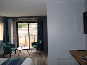 a hotel room with a bed and a table and chairs at Hôtel des Rochers in Perros-Guirec