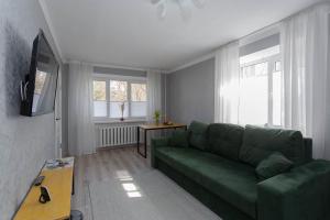 a living room with a green couch and a window at Apartment in the Center Gray Garden in Kaliningrad