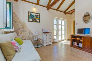 a living room with a white couch and a tv at Dubrovnik Chalets - 2 charming stone houses in Močići