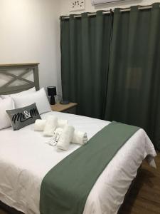 1 dormitorio con 1 cama grande y cortinas verdes en Omaha Luxury B&B/Spa, en Mthatha