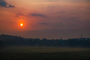 a sunset over a field with the sun in the sky at JK Lodge in Kottayam