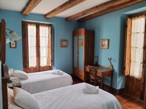 a blue room with two beds and a desk at Posada Magoria in Ansó