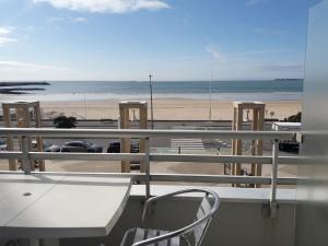 a balcony with a table and a view of a beach at Grand studio face mer baie de la Baule avec terrasse proche Thalasso et Parking in Pornichet