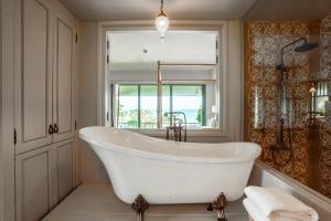 a bath tub sitting in a bathroom next to a window at Devasom Hua Hin Resort - SHA Extra Plus in Cha Am
