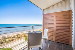 balcón con mesa, sillas y vistas al océano en Onslow Beach Resort, en Onslow